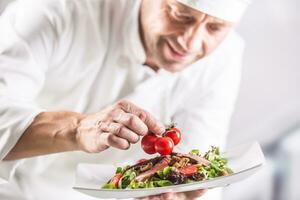 capocuoco nel il cucina di il Hotel o ristorante decora il cibo appena prima servendo foto