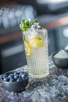 cocktail bevanda con mirtilli e menta a bancone da bar nel notte club o ristorante foto