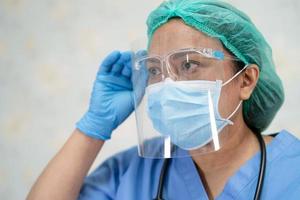 medico asiatico che indossa visiera e tuta in dpi nuovo normale per controllare il paziente proteggere la sicurezza infezione covid-19 focolaio di coronavirus nel reparto ospedaliero di quarantena.