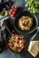 superiore di Visualizza italiano pasta spaghetti bolognese nel piatto e padella con pomodori e basilico foto