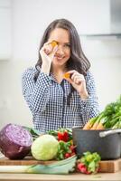 giocoso giovane donna Tenere fette di carota nel il cucina - dieta verdura e brughiera concetto foto