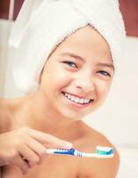 adolescenziale ragazza nel il bagno con spazzolino. dentale igiene foto