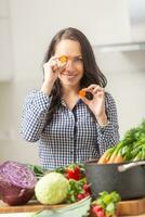 giocoso giovane donna Tenere fette di carota nel il cucina - dieta verdura e brughiera concetto foto