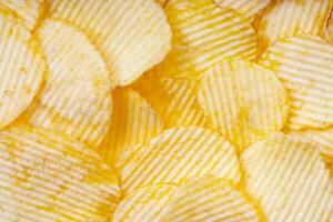 giallo croccante increspato Patata patatine fritte vicino su. cibo sfondo foto