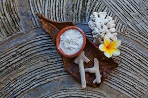 un' ciotola di bianca polvere e un' fiore su un' di legno tavolo foto