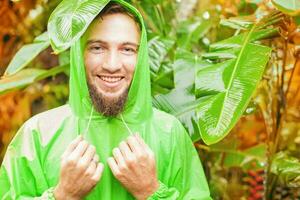un' uomo indossare un' verde impermeabile nel il giungla foto