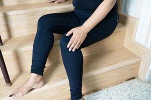 la paziente asiatica di mezza età della donna della signora cade dalle scale perché le superfici sdrucciolevoli e fanno male al ginocchio. foto