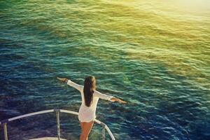 un' donna in piedi su il ponte di un' barca guardare su a il oceano foto