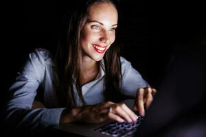 un' donna sorridente mentre utilizzando un' il computer portatile computer foto