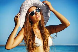 un' donna nel un' bikini e cappello su il spiaggia foto