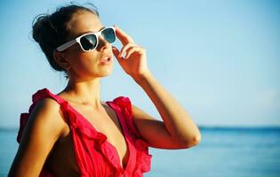 un' donna nel occhiali da sole in piedi su il spiaggia foto