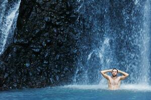 un' uomo in piedi nel davanti di un' cascata foto