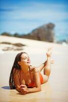 un' donna nel un arancia costume da bagno in piedi su il spiaggia foto