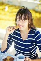 un' donna seduta a un' tavolo mangiare un' biscotto foto
