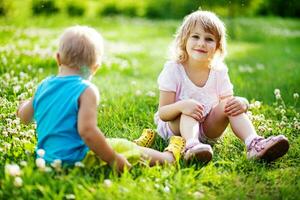 Due bambini seduta su il erba nel un' campo foto