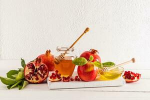 tradizionale prodotti per il ebraico nuovo anno vacanza. Miele, Melograno, mele su un' di legno bianca tavola e tavolo. il concetto di Roshashan. foto