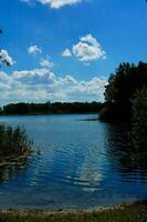 estate idilliaco paesaggio con un' lago sotto un' blu cielo su un' caldo soleggiato giorno foto