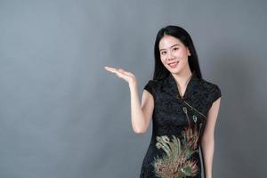 la bella giovane donna asiatica indossa il vestito tradizionale cinese con la presentazione della mano sul lato foto
