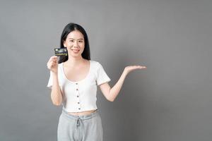donna asiatica con la faccia felice e che presenta la carta di credito in mano mostrando fiducia e sicurezza per effettuare il pagamento foto