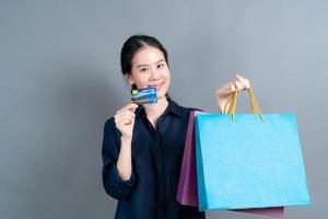 bella donna asiatica con borse della spesa e mostrando la carta di credito