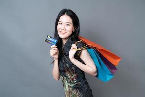 donna asiatica indossa abiti tradizionali cinesi con borsa della spesa e carta di credito foto