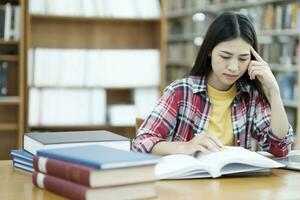 giovane Università alunno utilizzando il computer portatile per in linea apprendimento, ricerca e apprendimento a biblioteca. foto