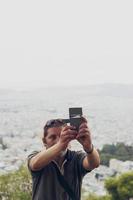 l'uomo sta facendo un selfie sulla collina, il paesaggio urbano è sullo sfondo foto