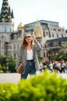 ragazza a piedi in giro città contro sfondo di bellissimo architettonico edifici. Torre su piazza nel batumi città nel Georgia. alto qualità foto. verticale composizione. foto