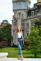 ragazza ispeziona luoghi d'interesse. ragazza a piedi in giro città contro sfondo di bellissimo architettonico edifici. donna in posa nel davanti di vecchio storico costruzione. Torre su piazza nel batumi città nel Georgia. foto