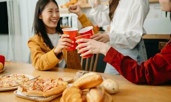 gruppo di amici fabbricazione divertimento a casa festa.loro seduta su scrivania nel vivente camera e mangiare Pizza. foto