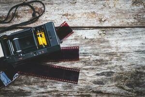 Manuale vecchio telecamera e film Usato per striscia su un vecchio di legno sfondo foto