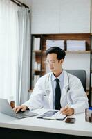 medico tecnologia concetto. asiatico medico Lavorando con mobile Telefono e stetoscopio nel moderno ufficio foto