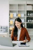 asiatico donna d'affari Lavorando nel il ufficio con Lavorando bloc notes, tavoletta e il computer portatile documenti nel ufficio foto