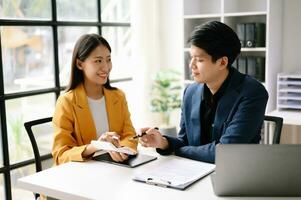 Due asiatico attività commerciale donna e uomo discutere investimento progetto Lavorando e pianificazione strategia con tavoletta il computer portatile computer nel ufficio. foto