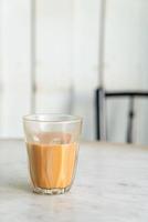 bicchiere di tè al latte tailandese caldo sul tavolo foto