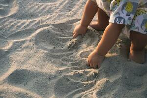 vicino su di ragazzo mani scavando su il spiaggia sabbia foto