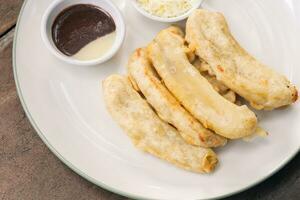 gustoso in profondità fritte Banana fette su di legno tavolo con cioccolato salsa. popolare strada cibo nel Sud est Asia foto