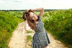 bellezza ragazza all'aperto godendo natura. bellissimo donna salto su estate campo con fioritura selvaggio fiori, sole luce. gratuito contento donna. foto