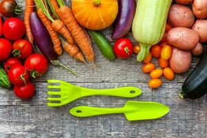 assortimento di diverse verdure biologiche fresche e attrezzi da giardinaggio su sfondo di legno in stile country. cibo sano vegano vegetariano mangiare concetto di dieta. l'orto locale produce cibo pulito. foto