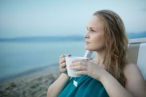 donna godendo un' tazza di tè a il mare foto