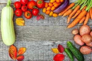 assortimento di diverse verdure biologiche fresche su sfondo di legno in stile country. cibo sano concetto di dieta vegetariana vegana. l'orto locale produce cibo pulito. cornice vista dall'alto spazio di copia piatta. foto