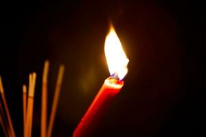 ardente incenso e rosso candele per pagare omaggio su un' buio sfondo durante Affamato fantasma Festival pagare omaggio per loro deceduto antenati foto