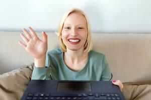 giovane donna agitando a il computer portatile e parlando per sua amici attraverso video chiamata, ragazza alunno parlando di video conferenza chiamata, femmina insegnante allenatore tutoraggio di webcam, in linea addestramento, e-coaching concetto foto