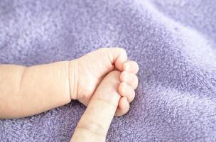 primo piano, la mano del bambino che tiene il dito di un genitore, simbolo di amore, protezione per un neonato. foto