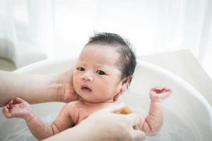 neonato viene lavato da sua madre usando la vasca a casa. foto