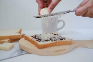 donna di mani fabbricazione crostini con burro e cioccolato su bianca sfondo. foto