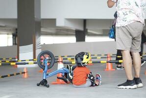 2 anni vecchio ragazzo riposo Il prossimo per equilibrio bicicletta e il suo papà dopo bicicletta gara nel un' parcheggio la zona, indietro Visualizza, dietro a Visualizza sparare. foto