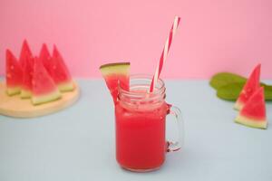 anguria frullato nel un' bicchiere vaso con cannucce come un' sfondo foto