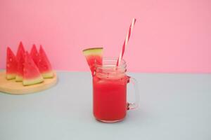 anguria frullato nel un' bicchiere vaso con cannucce come un' sfondo foto