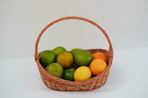 Limes e arance nel un' di vimini cestino su un' bianca sfondo foto